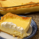 Slice of creamy lemon cream cheese dump cake with whipped topping on a blue plate