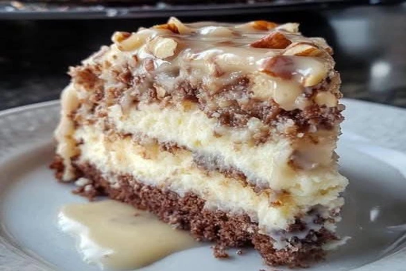 Slice of white German chocolate cake layered with cheesecake, topped with coconut pecan frosting.